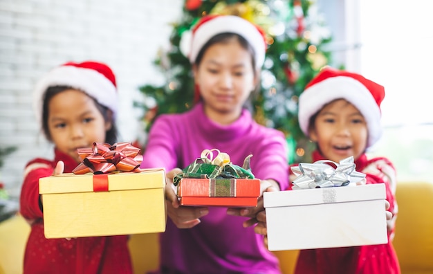 Enfants asiatiques tenant de belles boîtes-cadeaux et donnant dans la célébration de Noël