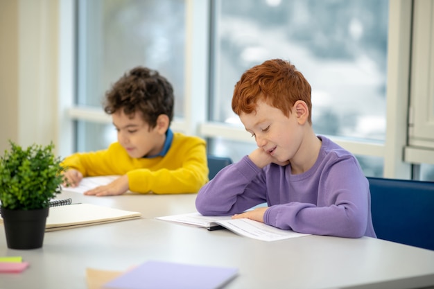 Enfants assis au bureau avec un camarade de classe