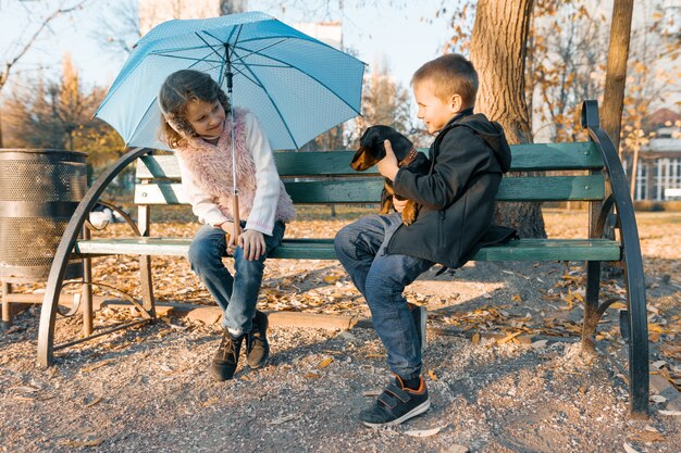 Photo enfants assis sur un banc avec un chien de teckel