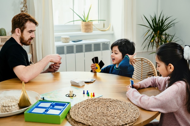 enfants assis ensemble à la table et jouant avec un jeu de société