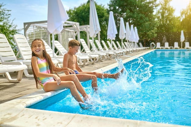 Enfants Assis Près De La Piscine éclaboussant De L'eau