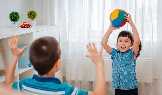 Enfants autochtones, un garçon et une fille jouent dans une salle de jeux pour enfants en lançant une balle.