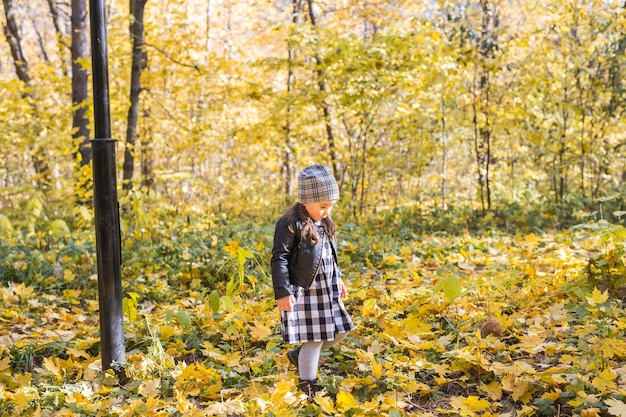 Enfants, automne, concept de personnes - jeune enfant marchant dans un parc d'automne et gardant des feuilles jaunes.