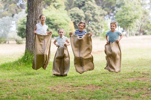 Enfants ayant une course en sac dans le parc