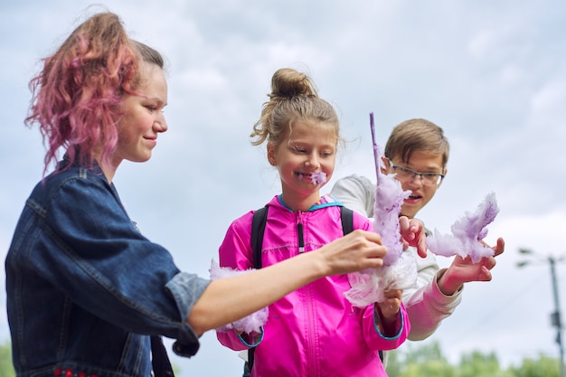 Enfants avec barbe à papa, trois enfants riant et mangeant un nuage rose sucré