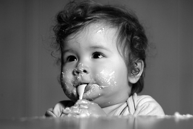 Enfants bébé manger avec un visage sale joyeux enfant enfant souriant mange lui-même avec une cuillère bébé manger w