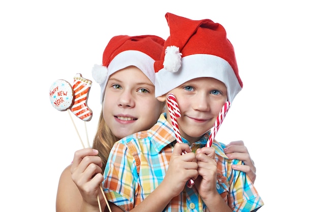 Enfants en bonnets rouges avec des bonbons de Noël isolés