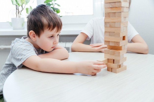 Enfants caucasiens garçon et fille jouant au jenga Jeu d'empilage de blocs Concept de jeu hors ligne pour activité familiale à la maison tout en restant à la maison pendant la quarantaine