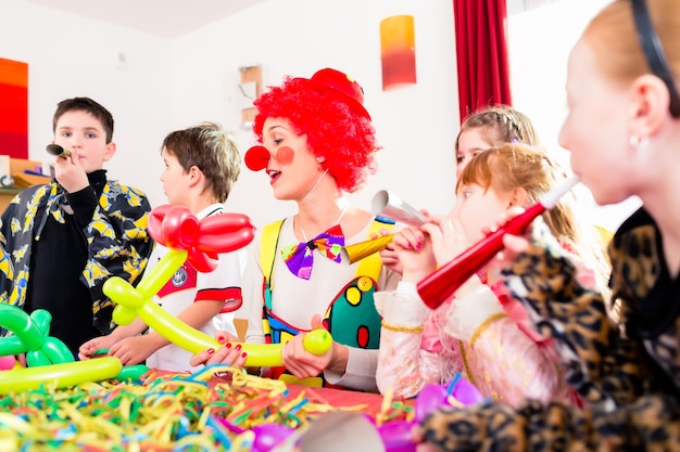 Photo les enfants célèbrent la fête d'anniversaire avec des bruits pendant qu'un clown est en visite pour divertir les enfants