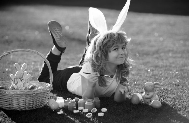 Des enfants célèbrent la Pâques en peignant des œufs. Un enfant en costume de lapin avec des oreilles de lapin à l'extérieur.