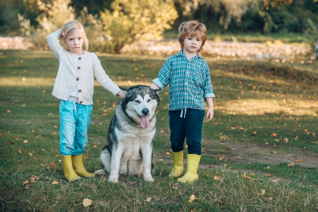 Enfants avec un chien mignon Garçon et fille jouant avec son chien sur la pelouse dans le parc Portrait en pied