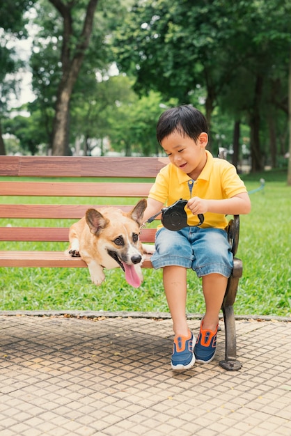 Enfants et chiens à l'extérieur. Petit garçon asiatique profitant et jouant dans le parc avec son adorable Pembroke Welsh Corgi.