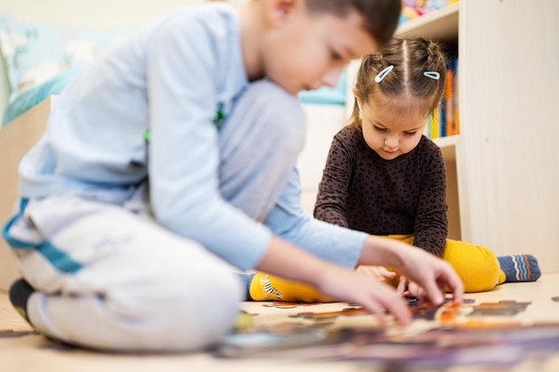 Enfants connectant des pièces de puzzle dans une chambre d'enfants sur le sol à la maison Loisirs d'activités familiales amusantes