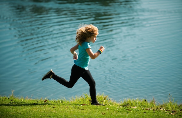 Photo les enfants courent ou courent près du lac sur l'herbe dans le parc les garçons coureurs courent dans le parc en plein air courir est un