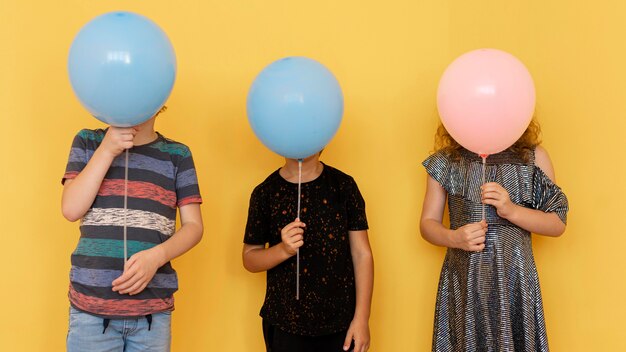 Enfants couvrant les visages avec des ballons