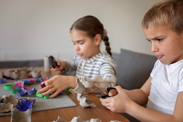 Les enfants créent une couronne de fleurs de Pâques dans des couleurs pastel à l'aide d'un mode de vie zéro déchet recyclé