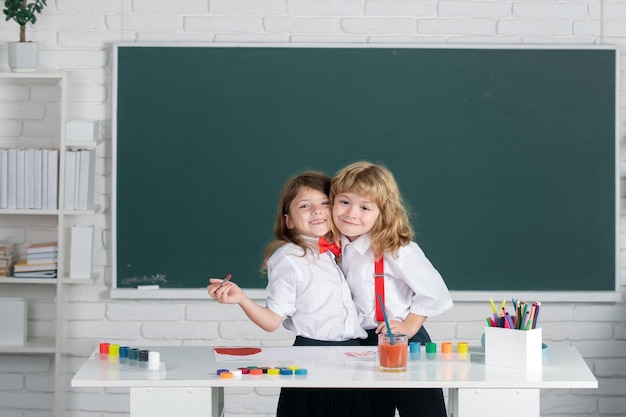 Enfants croissance créative écoliers fille et garçon étreignant embrasser et peindre avec des peintures couleur et