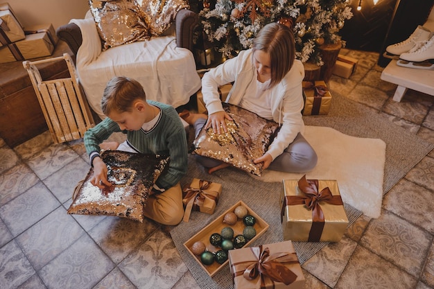 Enfants dans l'atmosphère de Noël du nouvel an. La famille est heureuse avec Noël et les cadeaux. Enfants à l'arbre du Nouvel An avec des cadeaux.