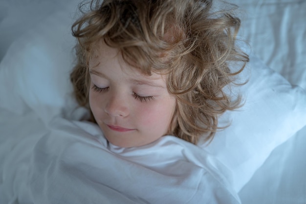 Enfants dans la chambre dormant sur le lit avec un drap blanc et un oreiller les yeux fermés