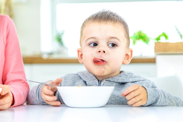 Les enfants dans la cuisine à table mangent des pâtes