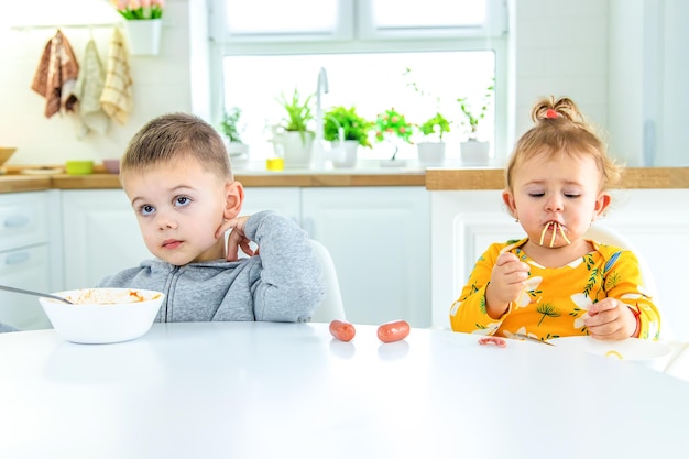 Enfants dans la cuisine à la table tournant la mise au point sélective des pâtes