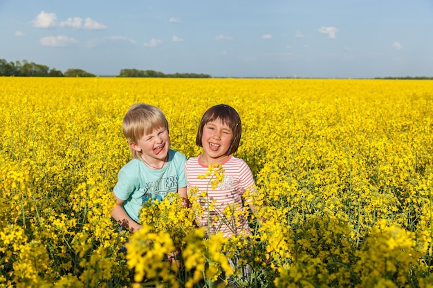 Enfants dans le domaine avec les fleurs jaunes fleuries du colza