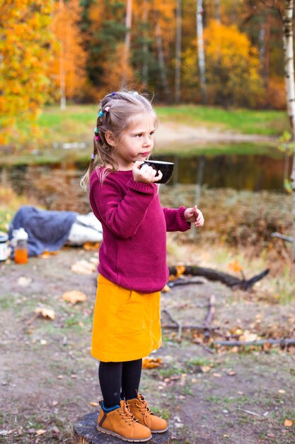 enfants dans la forêt d'automne sur un pique-nique en buvant du thé