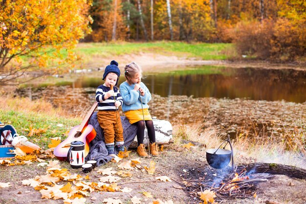 Enfants Dans La Forêt D'automne Sur Un Pique-nique Grill Saucisses Et Jouer De La Guitare