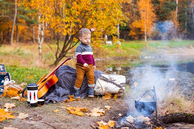 enfants dans la forêt d'automne sur un pique-nique grill saucisses et jouer de la guitare