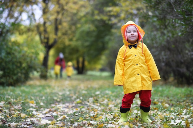 Les enfants dans le parc d'automne marchent dans des imperméables pendant la journée