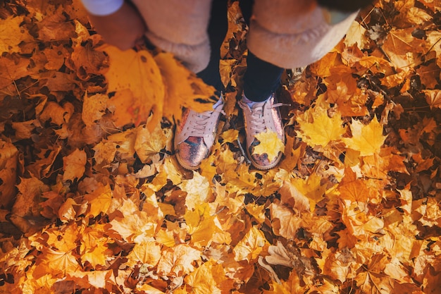 Enfants dans le parc avec les feuilles d'automne sur les chaussures. Mise au point sélective.