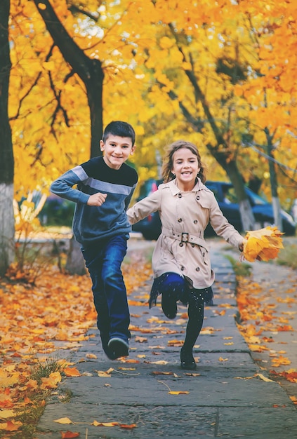 Enfants dans le parc avec des feuilles d'automne. Mise au point sélective.