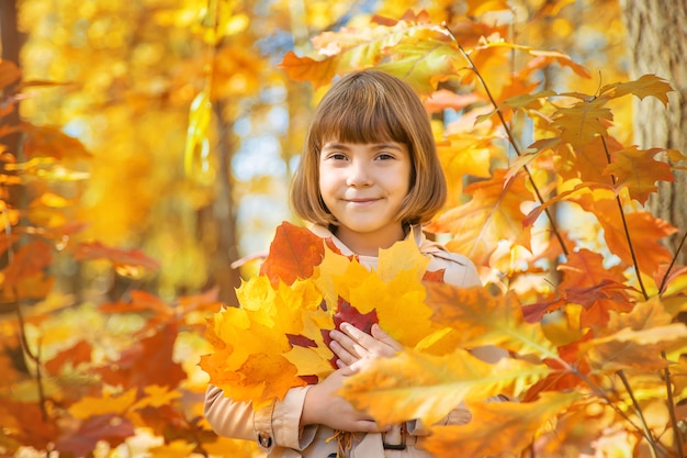Enfants dans le parc avec des feuilles d'automne. Mise au point sélective.