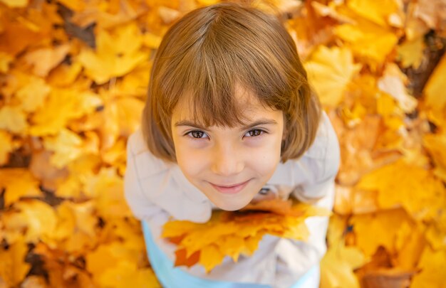 Enfants dans le parc avec des feuilles d'automne. Mise au point sélective.