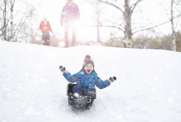 Enfants dans le parc en hiver. Les enfants jouent avec de la neige sur l'aire de jeux. Ils sculptent des bonhommes de neige et dévalent les collines.