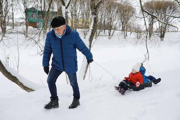 Enfants dans le parc en hiver. Les enfants jouent avec de la neige sur l'aire de jeux. Ils sculptent des bonhommes de neige et dévalent les collines.