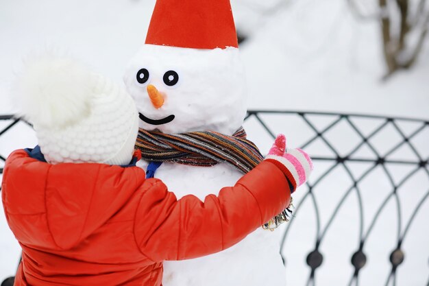 Enfants dans le parc en hiver. Les enfants jouent avec de la neige sur l'aire de jeux. Ils sculptent des bonhommes de neige et dévalent les collines.