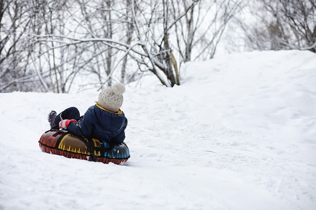 Enfants dans le parc en hiver. Les enfants jouent avec de la neige sur l'aire de jeux. Ils sculptent des bonhommes de neige et dévalent les collines.