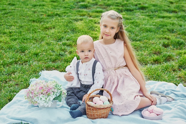 enfants dans le parc sur pique-nique de Pâques avec des oeufs et un lapin