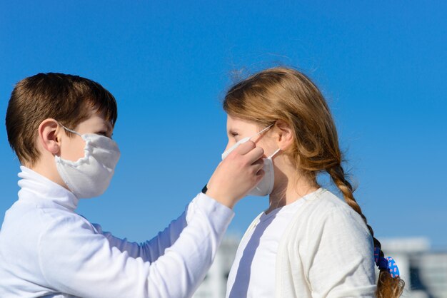 Enfants Dans Un Parc De La Ville Dans Un Masque Médical. Marcher Dans La Rue Pendant La Période De Quarantaine De La Pandémie De Coronavirus Dans Le Monde. Précautions Et Enseignement Aux Enfants