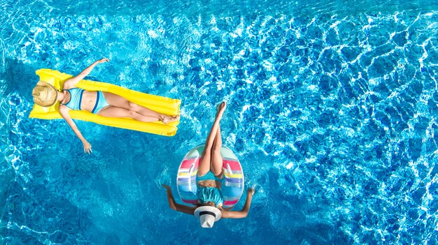 Enfants dans la piscine vue aérienne de drone fom ci-dessus, les enfants heureux nagent sur l'anneau gonflable et le matelas, les filles actives s'amusent dans l'eau en vacances en famille sur le lieu de vacances