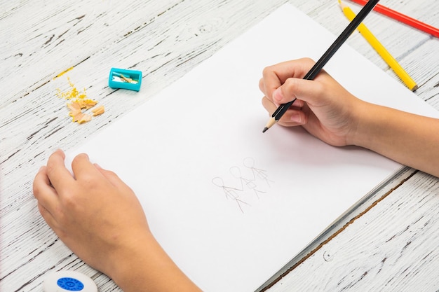 Enfants dessinant et beaucoup de crayons pour dessiner sur fond en bois.