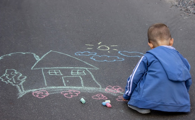 Enfants dessinant sur la maison familiale d'asphalte. Mise au point sélective