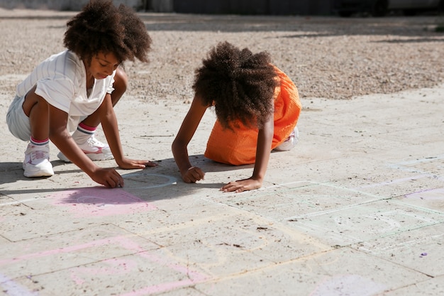 Photo enfants dessinant sur le trottoir plein coup