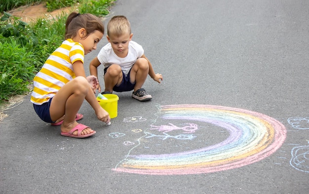 Les enfants dessinent sur le trottoir avec de la craie Très beau temps