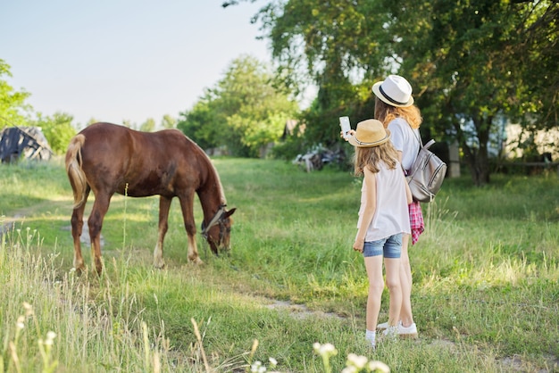 Enfants deux filles photographiant le cheval de la ferme sur smartphone.