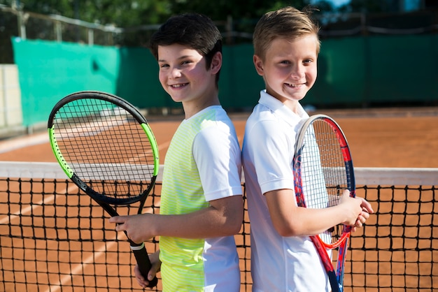 Photo les enfants dos à dos sur le court de tennis