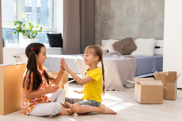 Des enfants drôles et excités courent à l'intérieur d'une grande maison moderne de luxe le jour du déménagement, des enfants mignons entrent dans une nouvelle maison, une jeune famille heureuse achète de l'immobilier