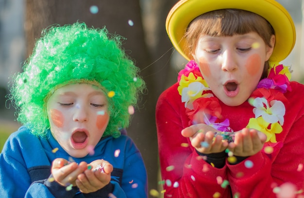 Enfants drôles filles célèbrent le carnaval en souriant et en s'amusant avec des confettis colorés