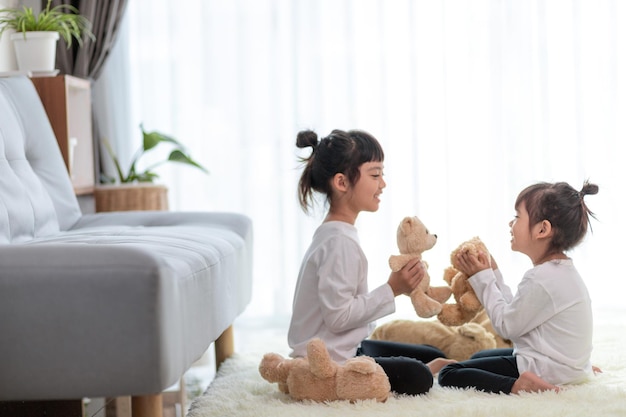 Enfants drôles mignons jouant avec un ours en peluche à la maison